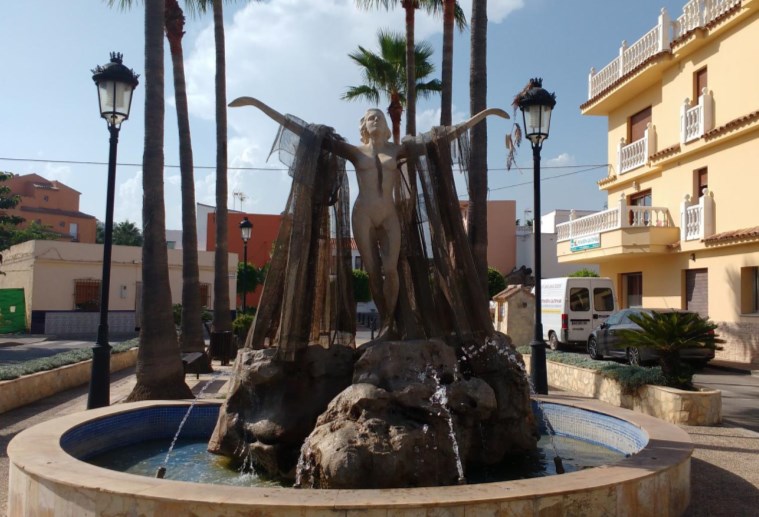 Plaza rectangular con flores, con palmeras…Y una bonita escultura
